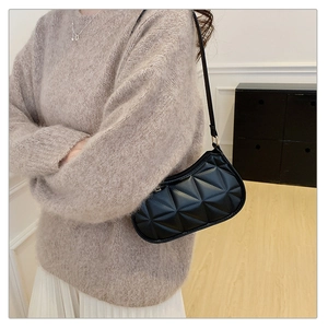 Detail of black geometric texture on faux leather underarm bag worn with casual outfit