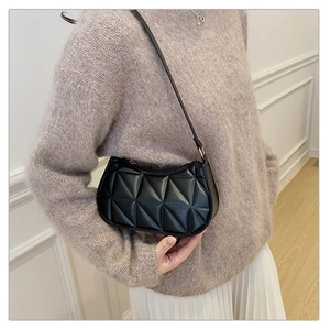 Close-up of black quilted leather shoulder bag with unique geometric triangular stitching
