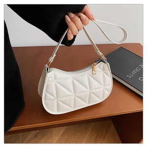 Detail of white quilted half-moon bag featuring triangle patterns and gold zipper