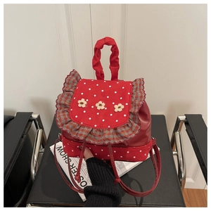 Detailed view of red polka dot mini backpack with floral accents and plaid ruffle trim
