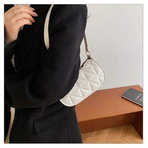 Detailed view of white quilted crescent bag with geometric stitching and slim shoulder strap