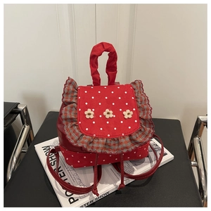 Detail of red polka dot backpack with floral accents and checkered ruffle edge trim