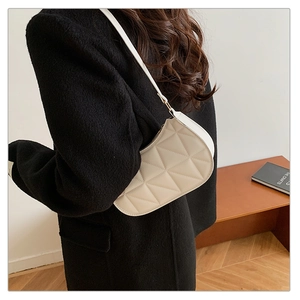 White crescent underarm bag with geometric triangular stitching shown on shoulder