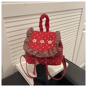 Detail of red polka dot backpack with floral lace trim and white yarn flowers