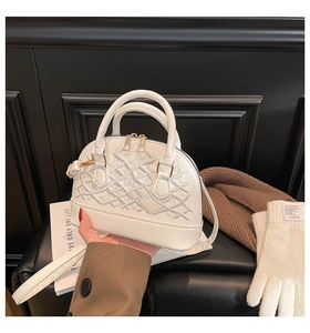 Detail of white shell-shaped handbag with quilted pattern and gold-tone hardware