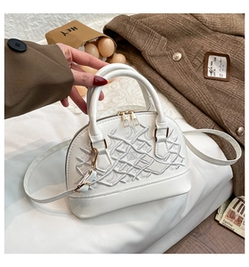 Detail of white shell handbag with intricate embroidery and elegant gold hardware
