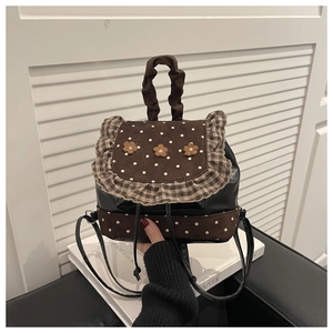 Detail of a mini backpack with brown polka dot suede, floral accents, and ruffled trim