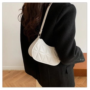 Close-up of white quilted crescent bag showing geometric texture and sleek shoulder strap