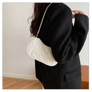 Detail of white quilted underarm bag with elegant rhombus pattern and sleek shoulder strap