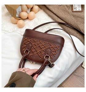 Detail of a brown shell handbag featuring intricate embroidery and textured faux leather