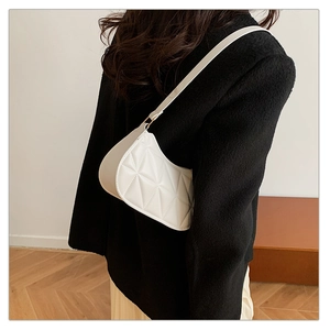 Detail of white quilted hobo bag with triangular stitching worn over a black coat