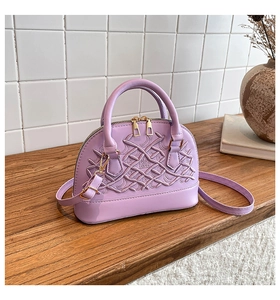 Close-up of lilac shell bag featuring intricate woven embroidery and golden hardware detail