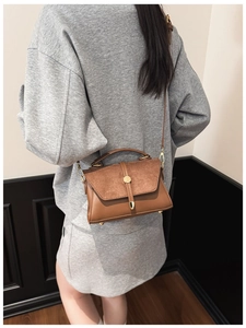 Braune Vintage-Umhängetasche aus Leder auf grauem Sweatshirt für einen modernen Look