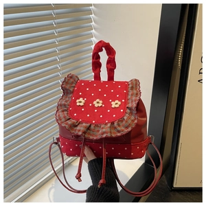 Detail view of red backpack featuring white polka dots and delicate beige floral accents