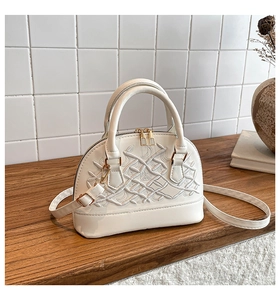 Detail of white shell handbag with crown embroidery, golden hardware and dual zippers