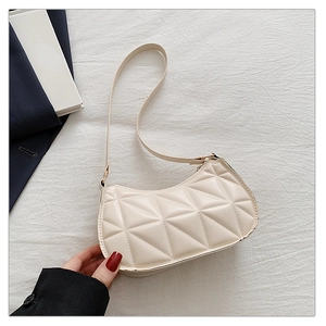 Detailed close-up of cream quilted crescent bag with gold hardware and rhombic pattern