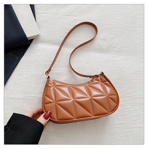 Close-up of brown hobo bag with triangular quilted stitching on a soft fabric background