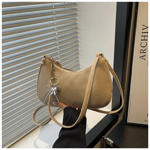 Detail of beige crescent shoulder bag featuring a silver bow charm and fine leather texture
