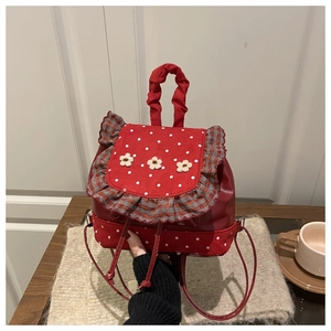 Detail of red polka dot mini backpack featuring 3D white flowers and ruffled edges