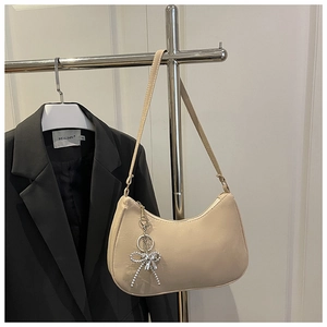 Detailed view of beige hobo bag with matte PU leather and a silver beaded bow charm