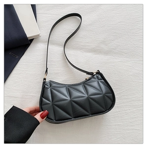 Detail of black geometric quilted handbag with gold buckle and smooth leather texture