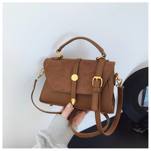 Detail der braunen Schultertasche mit matter Wildledermatte und goldener Metallschnalle