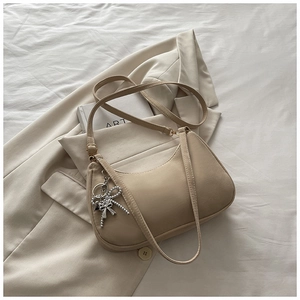 Close-up of beige matte PU leather shoulder bag with a silver bow charm detail