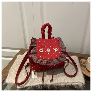 Detail of red polka dot backpack with ruffled edges and white floral embroidery