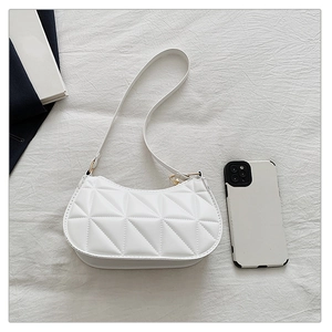 Macro shot of white quilted faux leather texture and gold buckle on a shoulder bag