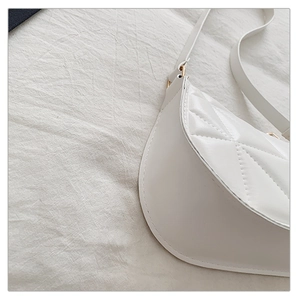 Detail of white half-moon shoulder bag featuring classic quilted rhombus pattern and gold hardware