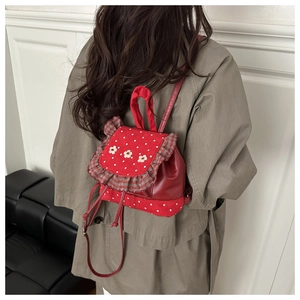 Close-up of red polka dot mini backpack with floral embroidery and ruffle trim details