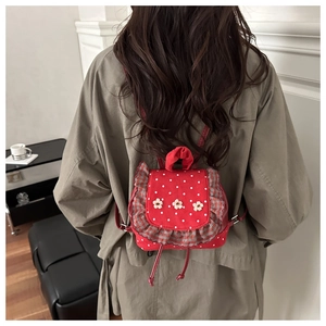 Detail of red polka dot mini backpack with floral accents and ruffled trim