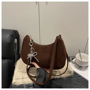 Detail of matte brown crescent bag featuring a delicate silver bow bead charm and strap