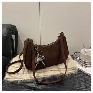 Detail of dark brown suede shoulder bag with silver bow charm and chain strap