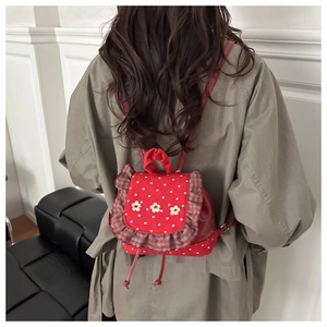 Detail of red polka dot mini backpack with floral accents and ruffle trim shown on back