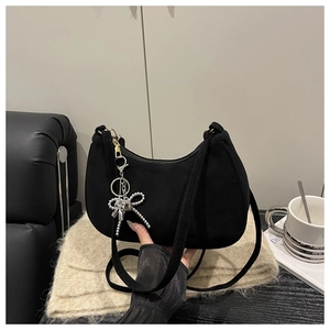Detail of black suede hobo bag with a silver bow tassel charm and metal chain strap