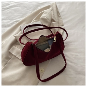 Internal storage view of the burgundy suede shoulder bag with daily essentials inside