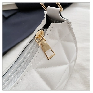 Detailed macro view of white quilted leather texture and shiny gold metal zipper closure
