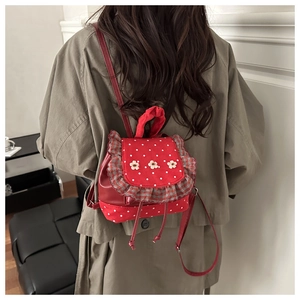 Detail of red polka dot mini backpack with floral accents and checkered frill trim