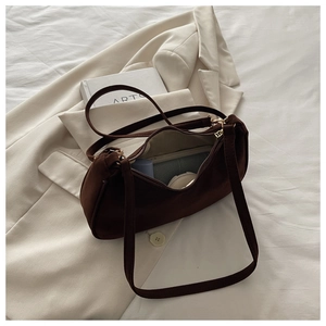 Detail of dark brown frosted suede shoulder bag interior with golden zipper and daily items