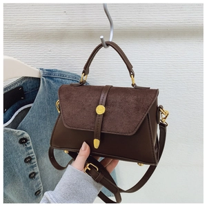 Nahaufnahme der dunkelbraunen Handtasche aus mattem Leder mit goldener Metallringschnalle