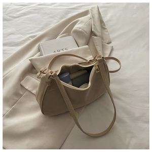 Detail of khaki crescent shoulder bag showing interior capacity and golden zipper hardware