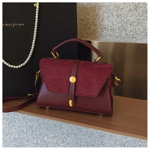 Detailansicht der weinroten Handtasche mit Goldschnalle und glatter Lederstruktur