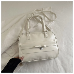 Detail of cream white faux leather handbag with bow decoration and silver heart charm