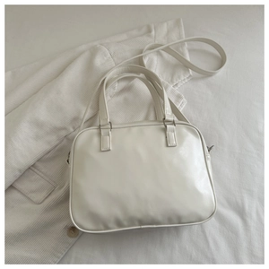 Detailed view of white glossy PU leather bag with silver hardware and dual handles