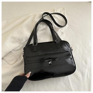 Close-up of black leather shoulder bag with a ribbon bow and heart metal pendant charm