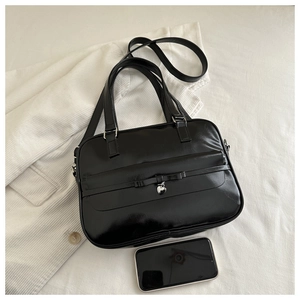 Detailed top view of black glossy shoulder bag with bow and silver heart pendant