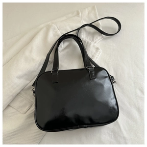 Top view of sleek black glossy underarm bag with silver hardware on striped fabric