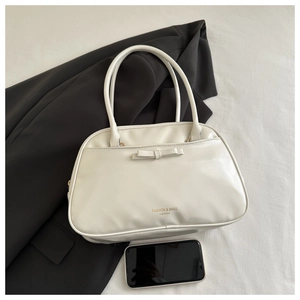 Close-up of white PU leather bag with bow detail and brand logo on a dark background