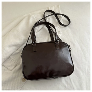 Flat lay of dark brown glossy PU leather shoulder bag with silver metal hardware detail